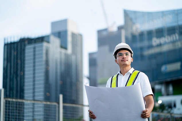 Construction Worker Examining Blueprints at Construction Site
