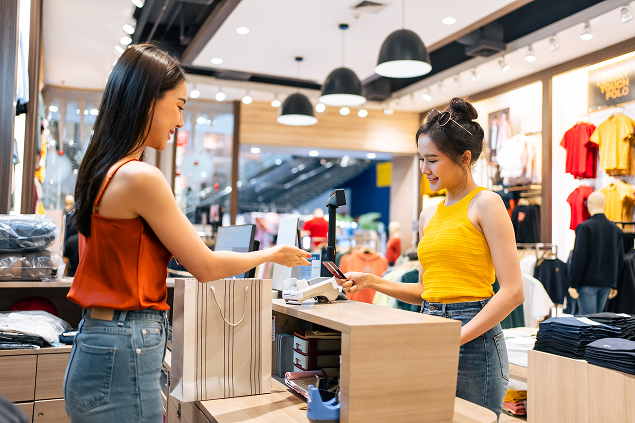 Asian young woman use credit card pay clothes product in shopping mall