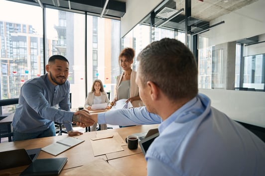 young-smiling-men-shake-hands-in-office-with-large-2022-09-01-21-56-49-utc-min